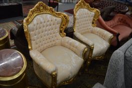 A pair of decorative modern gilt framed and button upholstered armchairs.