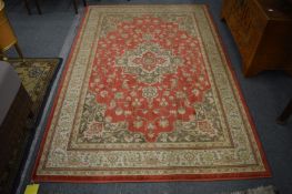 A Persian style machine made rug, rust ground with stylised decoration, 227cm x 154cm.