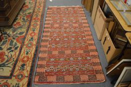 An African flat weave rug, red ground with stylised decoration, 211cm x 95cm.