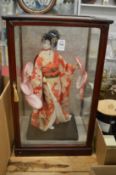 Glass display case containing a model of a Geisha girl.
