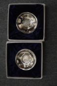 A pair of white metal coin dishes.