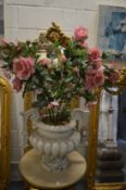 A large simulated stone twin handled urn containing artificial roses.