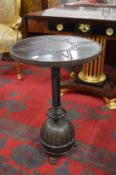 A decorative studded metal circular pedestal table.