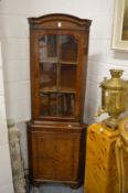 A reproduction walnut standing corner cabinet.