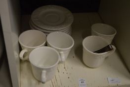 Cups and saucers and a pair of sugar tongs.