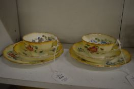 A pair of floral decorated porcelain trios.