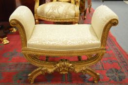 A pair of decorative gilt framed X framed window seat with classical style upholstery.