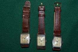 Three gentleman's tank shaped wristwatches with leather straps.