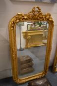 A decorative gilt framed mirror with ribbon and bow cresting, 150cm x 85cm.