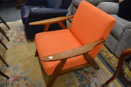 A modern stylish teak framed armchair with orange upholstery.