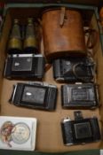 A collection of vintage cameras and binoculars.