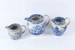 THREE 19TH CENTURY TRANSFER PRINTED BLUE AND WHITE JUGS, decorated with hunting scenes and river
