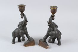 A PAIR OF GILT BRONZE CANDLESTICKS, modelled as elephants standing with one leg on a pyramid.