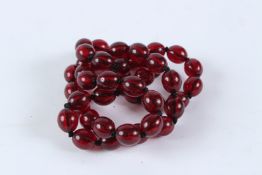 A STRING OF CHERRY AMBER BEADS. 80cms long.