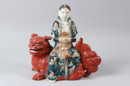 AN EARLY 20TH CENTURY CHINESE PORCELAIN FEMALE DEITY, seated on a lion dog. 25cms long.