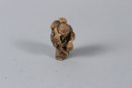 A JAPANESE STYLE TAGUA NUT NETSUKE carved in the form of a Sage. 3.5cms high.