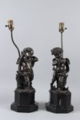 A PAIR OF CAST SPELTER CHERUB TABLE LAMPS, on black painted octagonal shaped wooden bases. 58cms