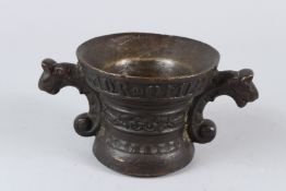 A 19TH CENTURY CAST BRONZE TWIN HANDLED MORTAR, with tiger head handles. 19cms wide.