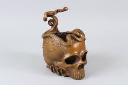 A BRONZE BOWL, modelled as a skull with snakes entwined. 11cms wide.