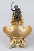 A BRONZE AND GILT BRONZE TABLE SALT, modelled as a cherub on a shell. 14cms wide.