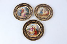 THREE ROYAL VIENNA PORCELAIN CABINET PLATES, each with richly gilded borders, painted with classical