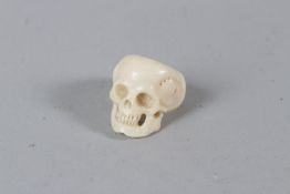 A CARVED BONE SKULL RING.