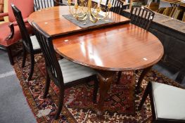 An Edwardian mahogany oval extending dining table with three leaves on carved cabriole legs with