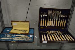 A cased pair of fish servers, a cased pair of scissors and a cased set of fish knives and forks.