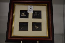 A framed and glazed group of four miniature silver items.