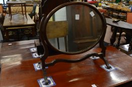 A mahogany oval toilet mirror.