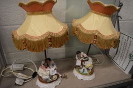 A pair of porcelain figural table lamps with shades.
