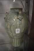 Large Chinese green glazed vase with strap work handles.