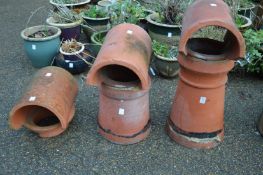 Three terracotta chimney pots with cowls.