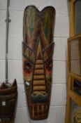 A large colourful painted wooden mask and another similar smaller one.