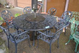 A black painted circular garden dining table with six armchairs and a parasol.