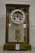 A late Victorian brass four glass mantel clock with visible escapement.