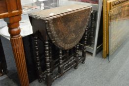 A small carved oak drop-leaf gateleg table with turned supports.
