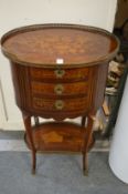 A French design marquetry inlaid mahogany three drawer oval shaped chest with galleried under tier.