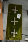 A collection of bronze crucifixes, mounted on backing boards.
