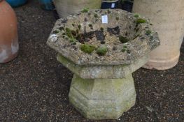 A small reconstituted stone octagonal shaped bird bath.