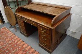 An early 20th century mahogany pedestal desk with tambour top, drop-flap sides.