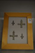 A collection of bronze crucifixes, mounted on backing boards.