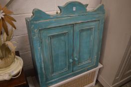 A bright blue painted pine two door hanging cupboard.