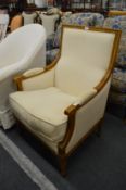 A French style oak framed armchair upholstered in a cream coloured material.