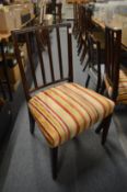 A pair of Georgian mahogany dining chairs with striped upholstered over stuffed seats.