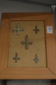 A collection of bronze crucifixes, mounted on backing boards.