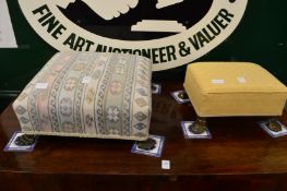 Two upholstered stools with brass feet.