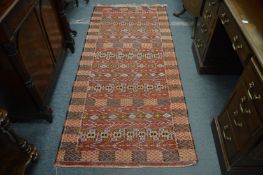 An Eastern rug, red ground with geometric decoration, 211cm x 95cm.