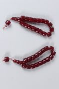 TWO STRINGS OF CHERRY AMBER STYLE BEADS.