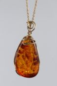 A SILVER GILT PENDANT AND CHAIN set with a large piece of amber.